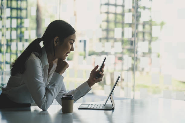 istock Side view of young woman office worker taking a break at office and using mobile phone. 1306429584