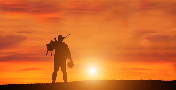 Silhouette Of A Solider Saluting Against the Sunrise. Concept - protection, patriotism, honor.