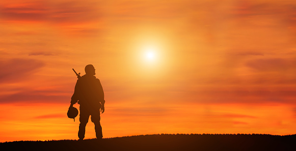 Silhouette Of A Solider Saluting Against the Sunrise. Concept - protection, patriotism, honor.