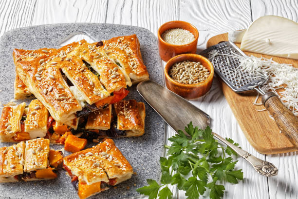 tarte américaine de pâte feuilletée de légumes avec le fromage de chèvre garni de graines de tournesol et de sésame remplies de légumes rôtis servis sur un fond en bois blanc, vue supérieure, plan rapproché - puff pastry pumpkin garlic cheese photos et images de collection