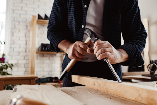istock Hands of a carpenter working with chisel and hammer 1306435066
