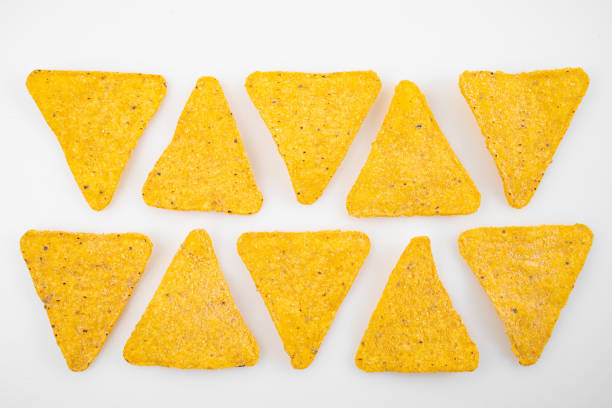 istock rows of Nachos on a white table. Mexican snack, corn tortilla chips. 1306437784