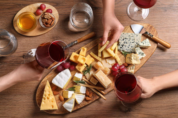 テーブルの上にワインとチーズプレートのグラスを持つ女性、トップビュー - appetizer ストックフォトと画像