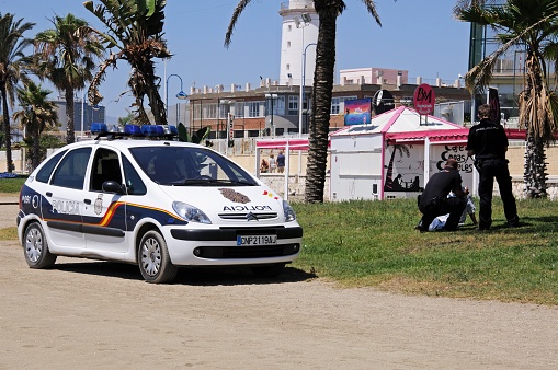 Two police officers talking to a vagrant on the edge of Malagueta beach, Malaga, Costa del Sol, Malaga Province, Andalucia, Spain, Western Europe.