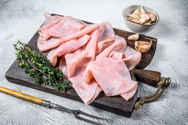 istock Ham Thin sliced on wooden cutting board with herbs. White background. Top view 1306439286