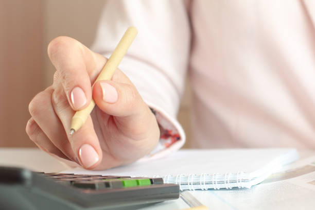 istock close up of woman hand with calculator counting and taking notes to notebook 1306442930