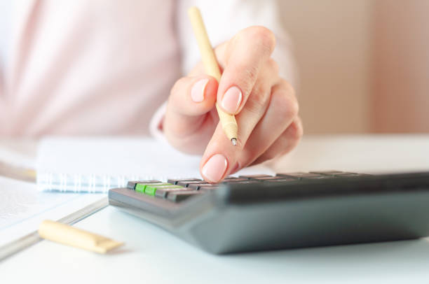 istock close up of woman hand with calculator counting and taking notes to notebook 1306442942