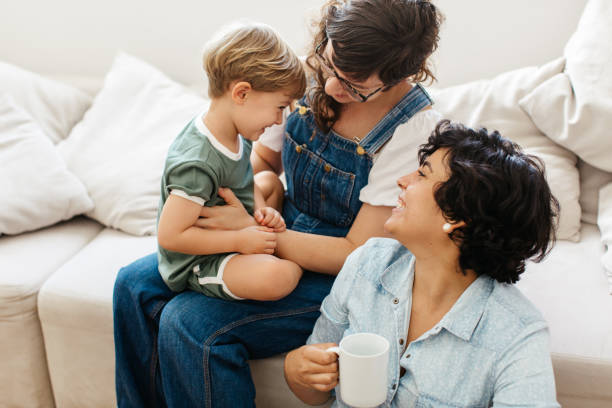 loving lesbian couple spending time with her son at home - homosexual family lesbian parent imagens e fotografias de stock