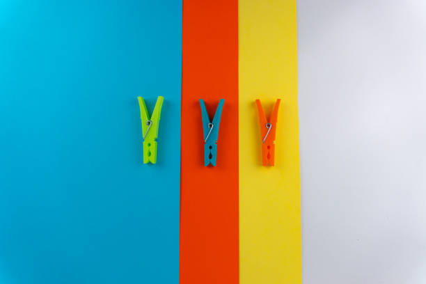 Top view of three different colored plastic clothespins on a background with four different colors