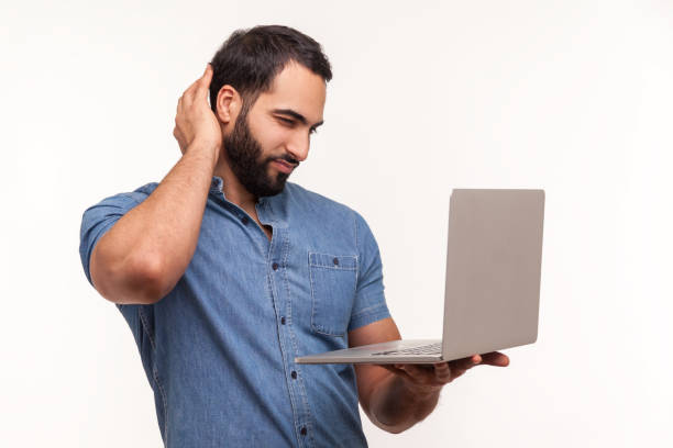 istock Thoughtful bearded man looking at laptop display rubbing his back of head, dont understand operation system, cant install application 1306450530