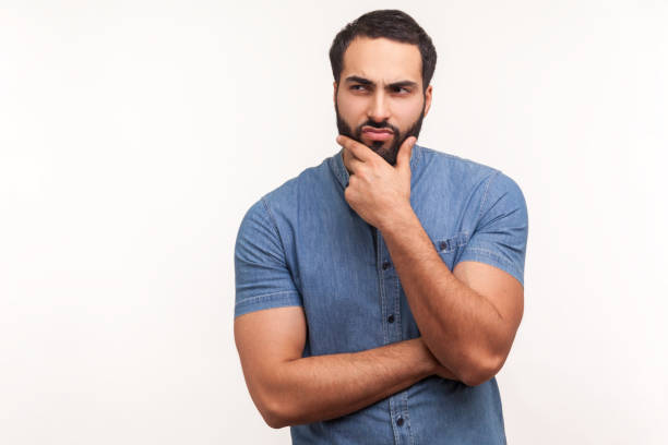 istock Thoughtful bearded man touching his chin, making difficult decision, facing with dilemma and trying to make choice, awkward situation 1306450544