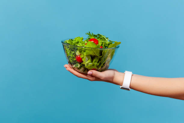 nahaufnahme weibliche hand hält große glasschüssel mit grünem salat aus frischen roten tomaten und salatblättern, bio-ernährung, gesunde ernährung, entgiftung diät - breakfast close up vegetarian food nature stock-fotos und bilder