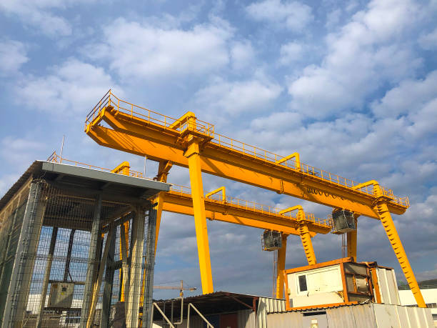 istock Gantry cranes opposite cloudy sky. Industrial lifting machinery. Hoist, winch 1306451721