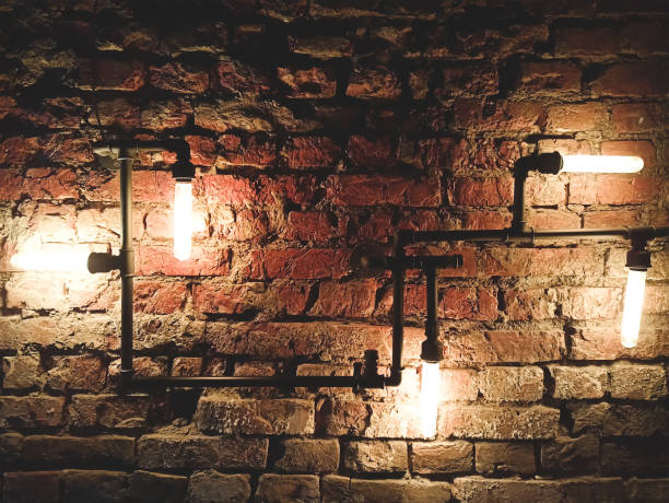 istock Interior design of vintage wall. Rustic design, brick wall with light bulbs and pipes, low lit bar interior 1306451822