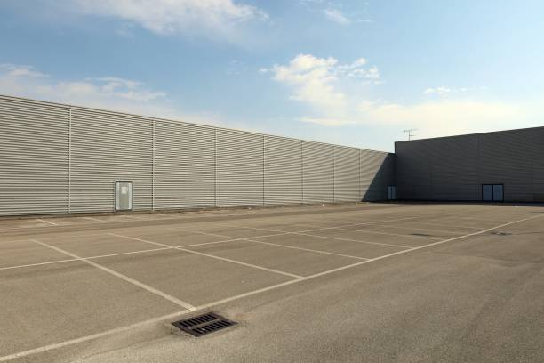 Large empty parking lot bordered by long aluminum clad walls.