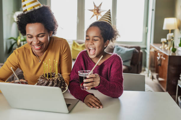 Online birthday celebration African American mother and daughter are in the kitchen celebrating birthday via video call virtual birthday celebration stock pictures, royalty-free photos & images