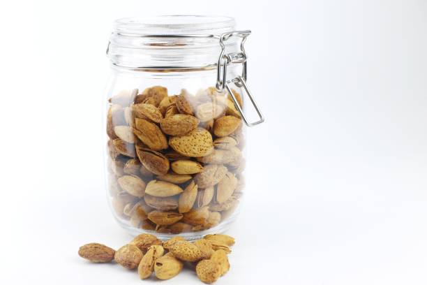 istock Unpeeled almonds in the glass jar. White background. 1306453630