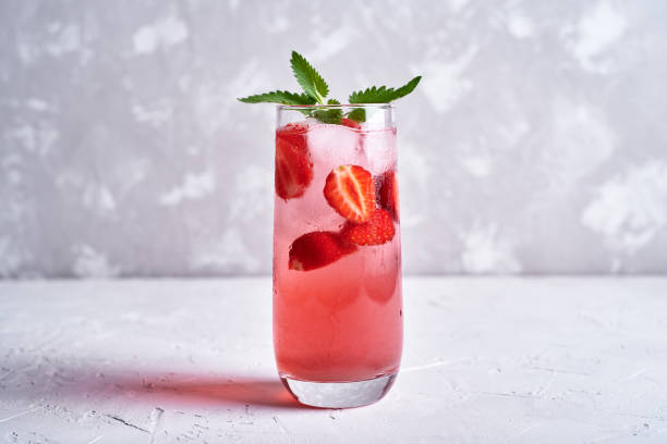 Fresh strawberry lemonade with ice and mint in glass on table, copy space. Cold summer drink. Sparkling glasses with berry cocktail stock photo