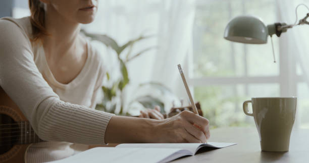 istock Woman playing guitar at home and composing music 1306453671