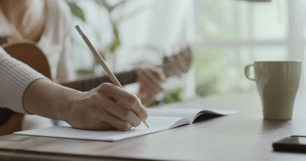 Woman playing guitar at home and composing music