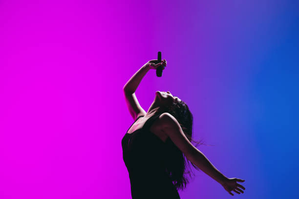 retrato de la joven cantante aislada sobre fondo azul rosa. - music microphone singer stage fotografías e imágenes de stock