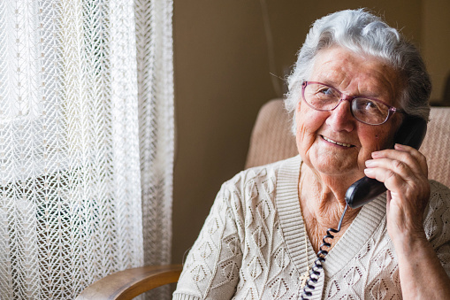 Smiling older lady wearing eyeglasses and using her phone