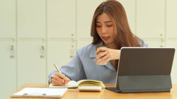 istock Businesswoman holding coffee cup while working with paperwork in office room 1306459500