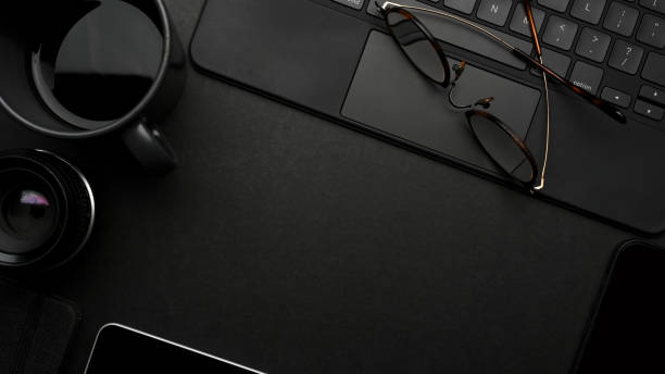 istock Dark creative flat lay workspace with eyeglasses, coffee cup, tablet keyboard and copy space 1306459543