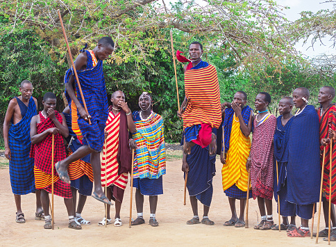 Masai-Mara tribe, Kenya - January 18, 2019: Group of african men of Masai tribe (indigenous tribe of Kenya) are dancing their ritual, national dance with high jumps in the traditional clothes. Outdoor. Africa.