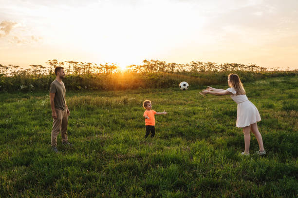 jeu heureux de jeune famille avec la bille extérieure - throwing football men ball photos et images de collection