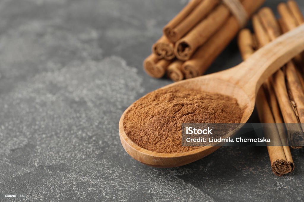 Aromatic cinnamon powder and sticks on grey table, closeup. Space for text Cinnamon Stock Photo
