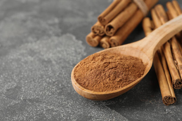 aromatic cinnamon powder and sticks on grey table, closeup. space for text - cinnamon imagens e fotografias de stock