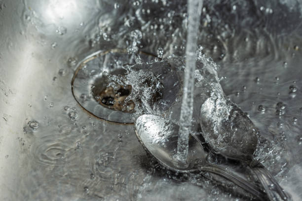 Photo of stream of water falling into a teaspoon and splashing down the sink