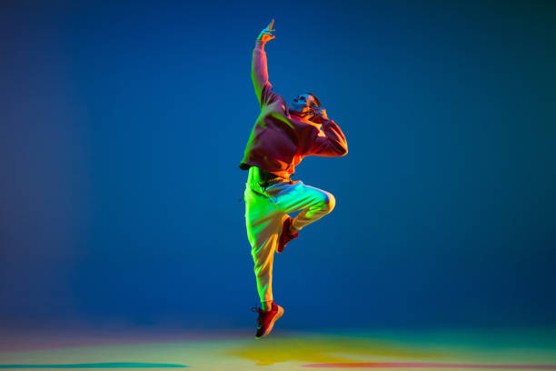 istock Young hip-hop dancer dancing isolated over blue background in neon light 1306462706