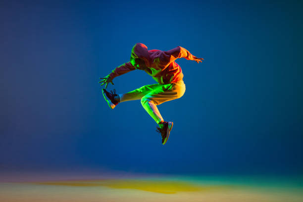 istock Young male dancer jumping isolated over on blue background in neon light 1306462730