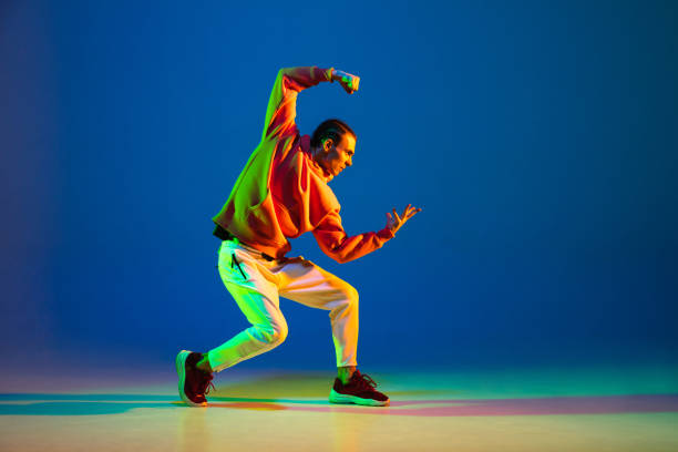 istock Young male dancer posing isolated over blue background in neon light 1306462751