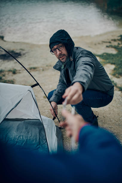 istock Two hikers adjusting tent on camping trip while standing in a nature. 1306464502