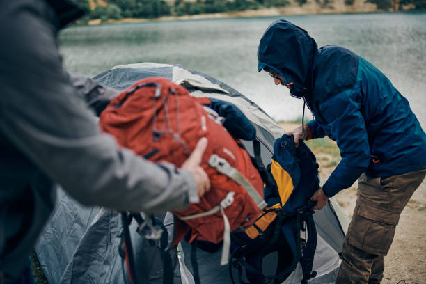 istock Two men on a camping trip in the nature putting backpack in a tent. 1306464569