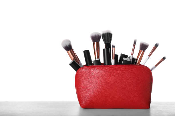 istock Bag with makeup brushes and cosmetic products on grey table against white background. Space for text 1306464693