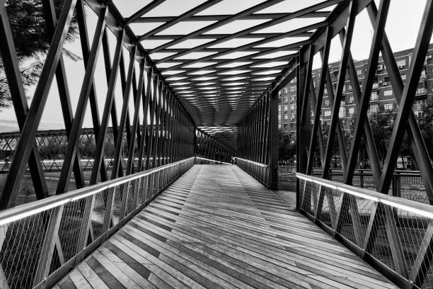 istock Bridge with railings formed by interlocking meyal bars forming a latticework and wooden floor. Black and white photo.. 1306467953