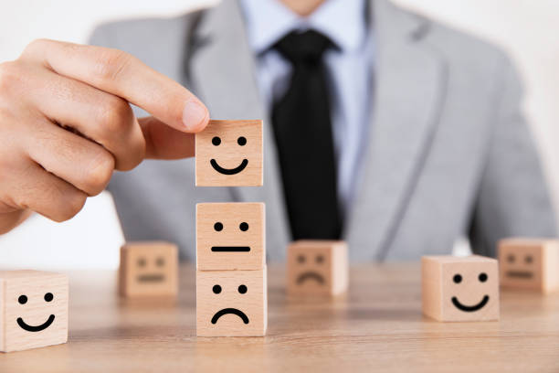 istock Close up Male Hand Choosing Smiley Face Icon on Wood Cube 1306470986