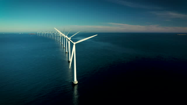 Coastal wind turbines at the oceanic windmill Middelgrunden, situated just outside Copenhagen. These iconic turbines, which can be seen from most places within this capital city, are a symbol of a future with green cities and sustainable energy in Denmark. Footage captured with drone in 4k resolution
