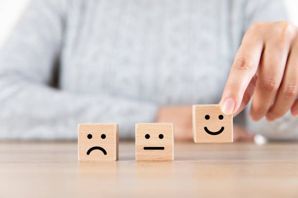 istock Close up Woman Hand Choosing Smiley Face Icon on Wood Cube 1306472024