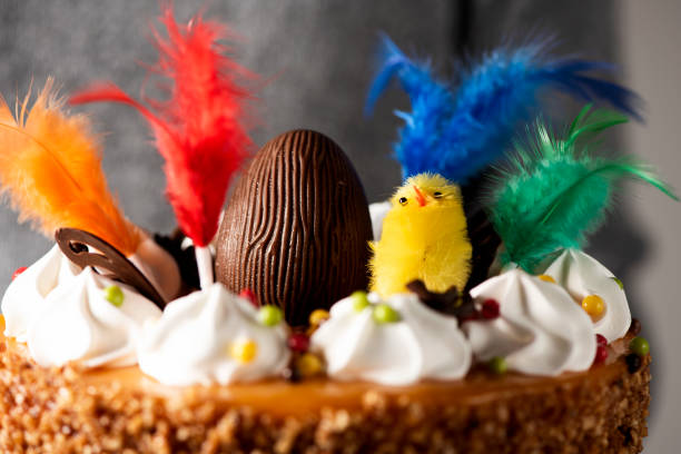 man carrying a spanish mona de pascua cake closeup of a young man carrying a spanish mona de pascua, a cake eaten on Easter Monday, ornamented with a chocolate egg, a plush chick and feathers of different colors easter cake stock pictures, royalty-free photos & images