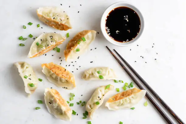 Gyoza fried chinese dumplings served with scallions, sesame seeds and soy sauce. Top view. Asian cuisine food