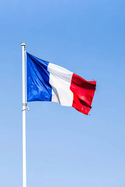 Photo of French flag waving in the wind on a sunny day.