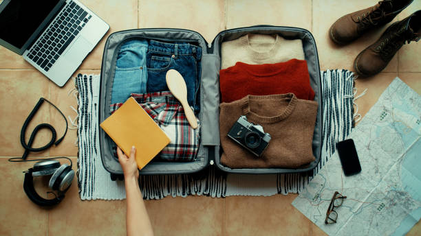 Woman packs suitcase for travel or adventure Woman packs winter themed suitcase for autumn holiday. Vacation preparation, careful bag packing. Millennial generation z travel blogger pack suitcase with social media vintage camera, sweater, laptop packing stock pictures, royalty-free photos & images