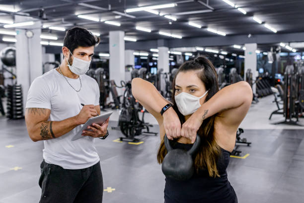 istock Trainer taking notes on tablet during evaluation of active student with facial mask 1306482224