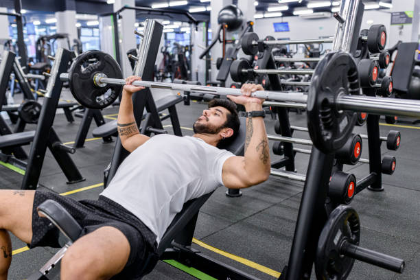 istock Handsome man doing biceps lifting barbell in a gym. Side view 1306483132