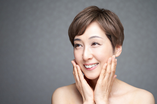 A middle-aged Japanese woman who puts her hands on her cheeks with a smile